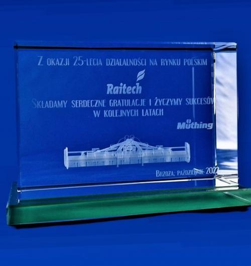 szklana statuetka z okazji 25-lecia z kosiarką w 3D na zielonej szklanej podstawce Kosiarka grawerowana jako model 3D, dedykacja grawerowana wewnątrz szkła kryształowego Szklany upominek firmowy z okazji jubileuszu z grawerem 3D