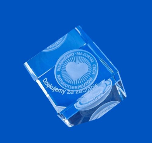 szklany upominek biznesowy z okazji jubileuszu Warmińsko-Mazurskiego Cechu Naturoterapeutów Kryształowy sześcian ze ściętym narożnikiem z wygrawerowanym sercem w 3D i logo Cechu Szklana kostka z grawerem 3D logo jako drobny firmowy upominek