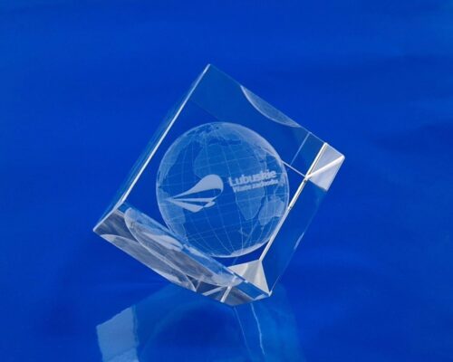 promotion of the region - a glass gadget with the logo of the Lubuskie Voivodeship Glass cube with a cut corner with 3D engraving, inside the crystal cube there is an engraved 3D globe and the logo of the Lubuskie Voivodeship 3D crystal with logo on the desk Elegant modern gadget with 3D engraving