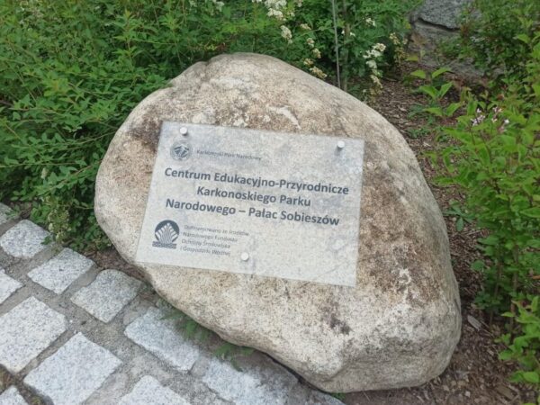 szklana tablica okolicznościowa przymocowana do bardzo dużego kamienia, który jest umieszczony na terenie Centrum Edukacyjnego Pałacu w Sobieszowie - Karkonoski Park Narodowy