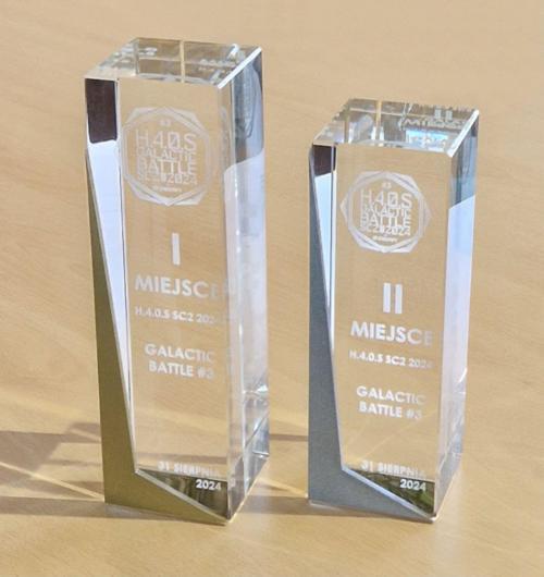 szklana statuetka z metalem na turniej GALACTIC BATTLE Kryształowy prostopadłościan z ozdobnym elementem ze stali w 3 kolorach, za zajęcie pierwszego, drugiego i trzeciego miejsca. Metal sprawia, że statuetka jest jeszcze bardziej ekskluzywna. Metal malowany na złoty kolor dla najlepszego gracza. Logo i napisy są wygrawerowane laserem 3D wewnątrz szkła Zaprojektuj z nami nowoczesne, szklane nagrody, które będą łączyć różne techniki wykonania podkreślając charakter Twojego wydarzenia