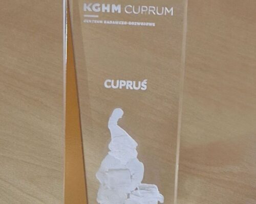 glass award with metal with Cuprus the dwarf, custom made for KGHM CUPRUM Research and Development Center The statuette made of crystal glass tapers slightly towards the top, on the side there is a decorative element made of stainless steel painted copper color The Cuprus the dwarf engraved inside the glass, the whole creates a very exclusive corporate gift Laser 3D manufacturer of awards custom made since 2000, Zielona Gora