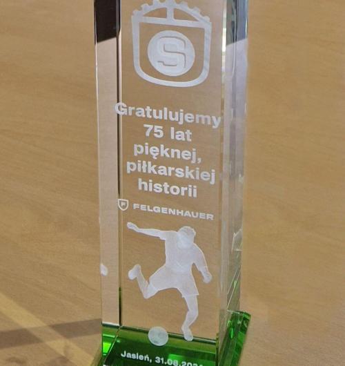 szklana statuetka z piłkarzem 3D z okazji jubileuszu klubu Stal Jasień na podstawce z zielonego kryształu Podstawka z zielonego kryształu doskonale imituje murawę, a refleksy światła sprawiają, że statuetka jest pięknie, naturalnie podświetlona Piłkarz jest wygrawerowany jako trójwymiarowy model Logo i życzenia są wygrawerowane na różnych głębokościach w bryle szkła kryształowego To wyjątkowy, personalizowany prezent z okazji 75-lecia klubu piłkarskiego Stal Jasień Wysokiej jakości szkło kryształowe, precyzyjne grawerowanie laserem 3D nadaje statuetce ekskluzywności Podaruj niezapomnianą, pamiątkową statuetkę od producenta z dwudziestotrzyletnim doświadczeniem w grawerowaniu 3D