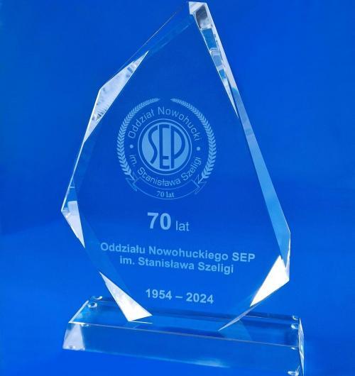 szklane statuetki okolicznościowe z okazji jubileuszu 70-lecia Oddziału Nowohuckiego Stowarzyszenia Elektryków Polskich SEP Jubileuszowa statuetka ze szkła kryształowego z bardzo eleganckimi ozdobnymi szlifami po bokach, na podstawce w kształcie trapezu Specjalnie przygotowane na rocznicę jubileuszowe logo grawerowane wewnątrz szkła laserem 3D Statuetka zapakowane w granatowe opakowanie zamykane na magnes z błyszczącym materiałem wewnątrz etui Statuetki ze szkła kryształowego to doskonały materiał, żeby podkreślić ważne wydarzenie w Twojej firmie Zamów u producenta, pierwszej firmie w Polsce, która zajmuje się grawerowaniem 3D już od 2000 roku