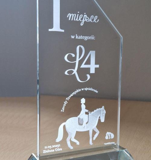 szklana statuetka trofeum dla zwycięzcy w Towarzyskich zawodach w ujeżdżaniu koni zorganizowanych w Zielonej Górze Szklana statuetka z ciekawym ścięciem na górze, umieszczona na trapezowej podstawce W statuetce wygrawerowany jeździec na koniu w eleganckiej postawie oraz nazwa kategorii i zawodów Projekt wygrawerowaliśmy laserem 3D wewnątrz szkła Grawerowanie 3D pozwala na zachowanie gładkich powierzchni szkła, ponieważ wzór jest umieszczony w środku Organizujesz zawody i potrzebujesz nowoczesnej szklanej statuetki? Być może ten kształt szklanej nagrody sportowej przypadnie Tobie do gustu Laser 3D producent statuetek od 2000 roku