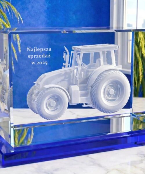 Szklana statuetka z grawerowanym traktorem 3D na niebieskiej podstawie – kryształowa nagroda biznesowa za najlepszą sprzedaż w 2025 roku. Trójwymiarowy model traktora został wygrawerowany wewnątrz kryształowego szkła w kształcie prostopadłościanu o najwyższej przezroczystości kryształowa bryła jest umieszczona na szklanej, niebieskiej podstawce obok traktora jest napis „Najlepsza sprzedaż w 2025” Szklana nagroda biznesowa z ciągnikiem 3D od Laser 3D Wybierz prestiżowe szklane statuetki od pierwszego producenta w Polsce – Laser 3D Zielona Góra